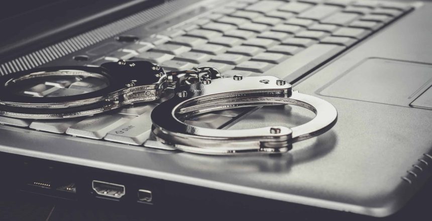 handcuffs on the laptop cyber crime concept