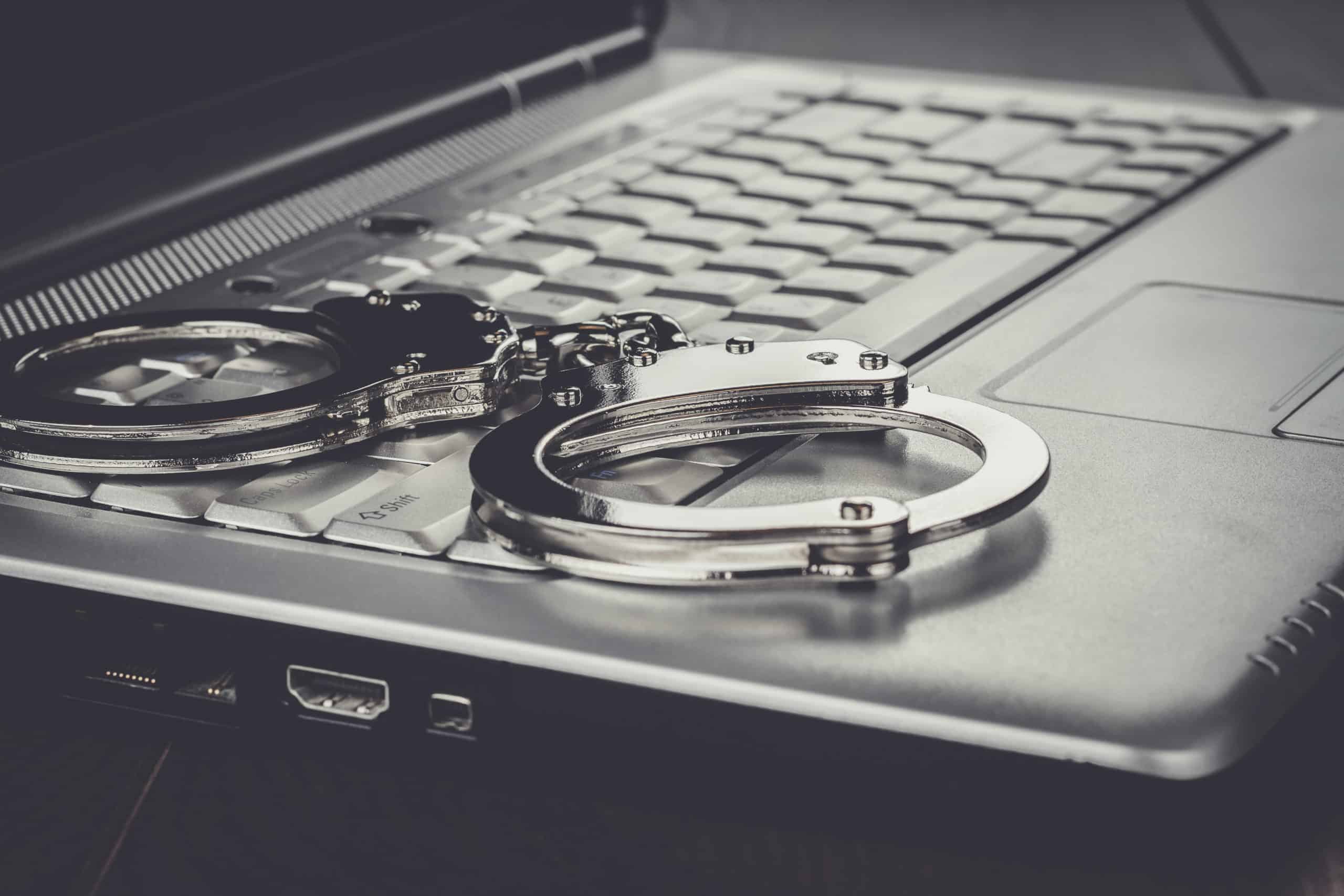 handcuffs on the laptop cyber crime concept